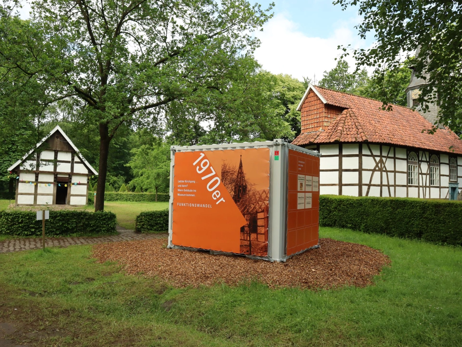 Die Dorfkirche und die Schule im Museumsdorf Cloppenburg mit einem Ausstellungscontainer zum 100-jährigen Jubiläum