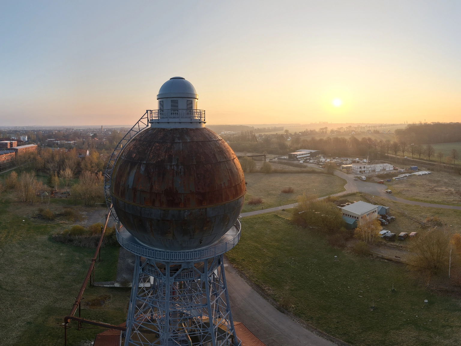 wow!CLUB: wowTower (Kugelwasserturm) und wowCampus (im Hintergrund rechts) auf dem Gelände der ehemaligen Ilseder Hütte. Luftbildaufnahmen bei Sonnenaufgang.