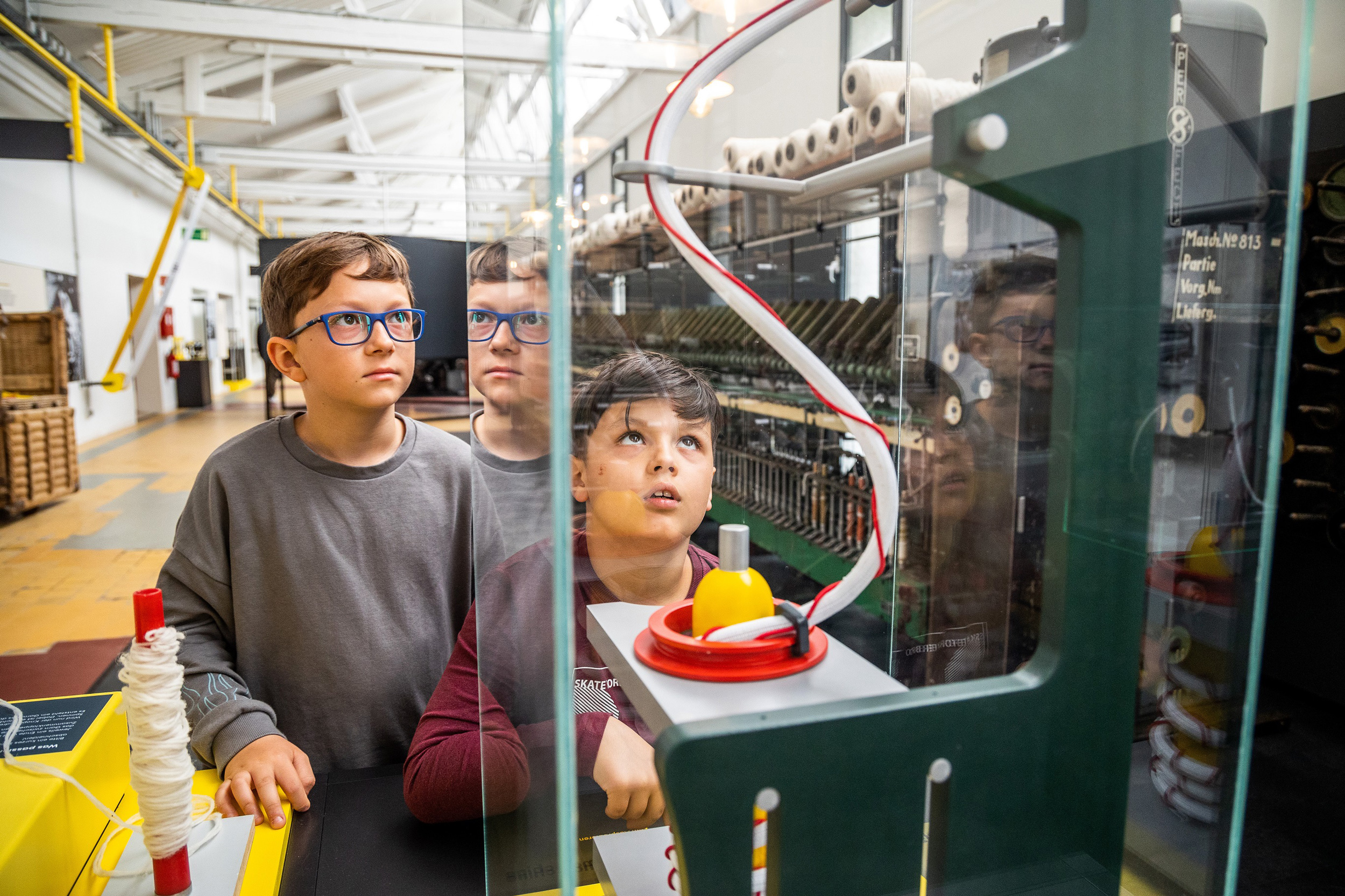 Impression der Dauerausstellung im Fabrikmuseum Delmenhorst: Kinder entdecken die Kammgarnproduktion
