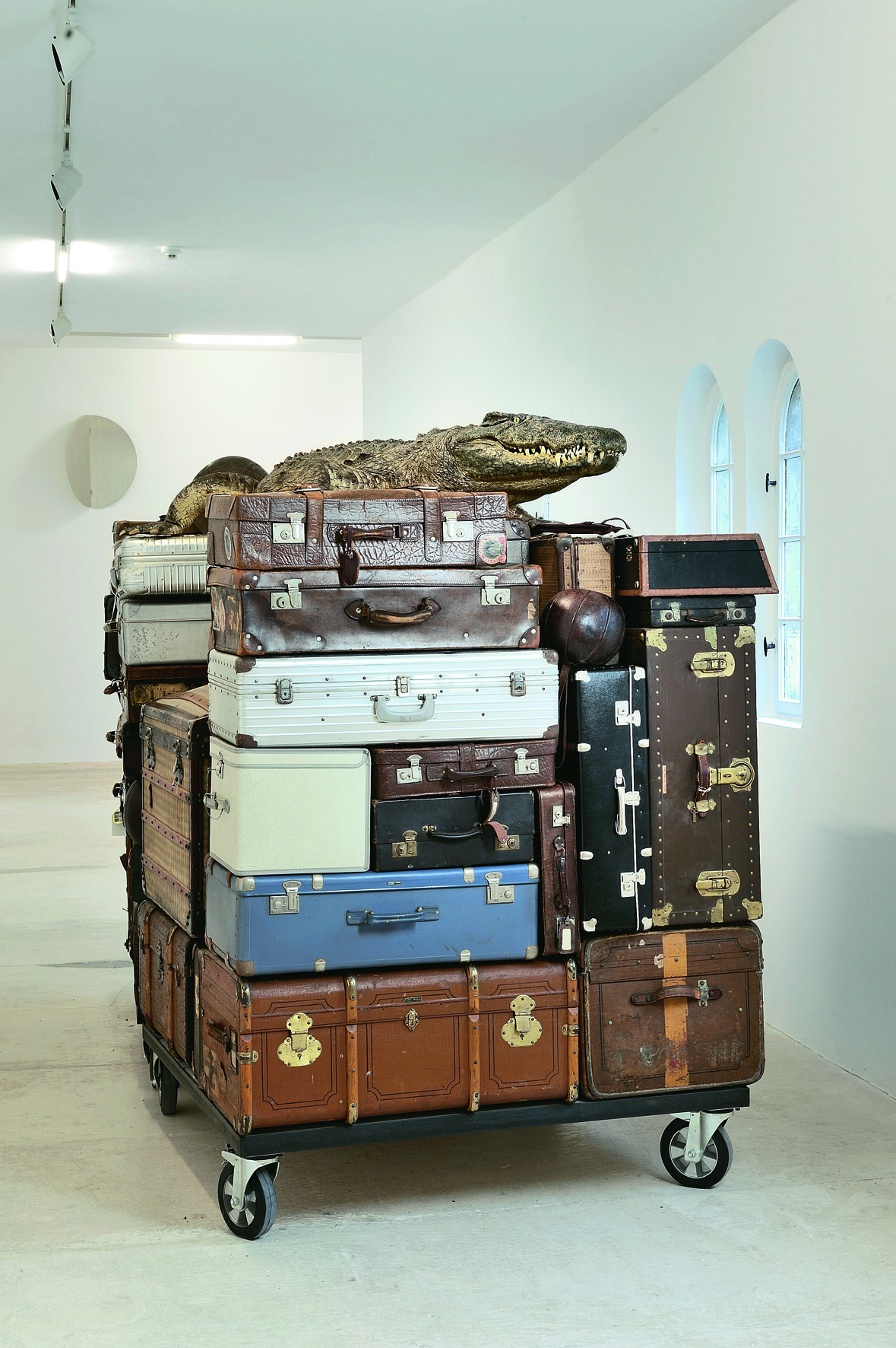 Christiane Möbus, NELLY, 2007<br/>Präpariertes Krokodil, diverse Koffer, Taschen, Transportkisten, Medizinbälle, ein Paar Kinderhandschuhe, zwei Transportwagen, Stahl, Holz, 215 x 332 x 142 cm